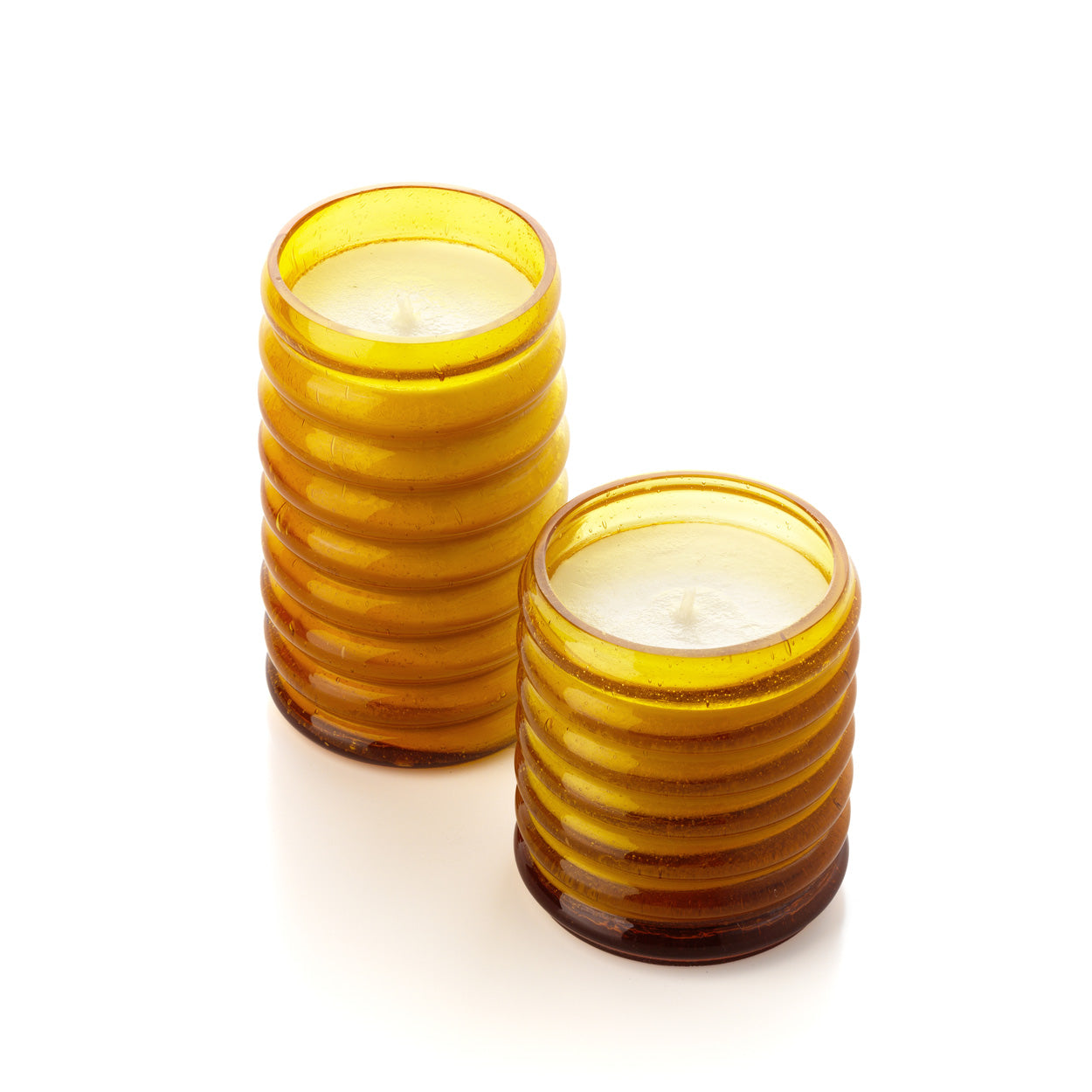 Two yellow glass candle holders with candles inside on a white background