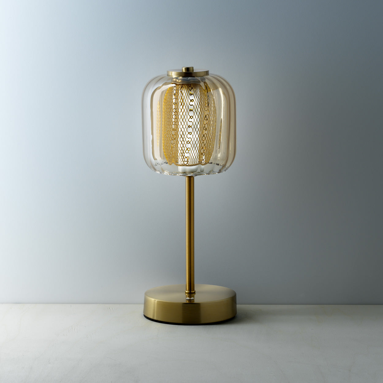 Gold table lamp with a textured glass shade on a neutral background