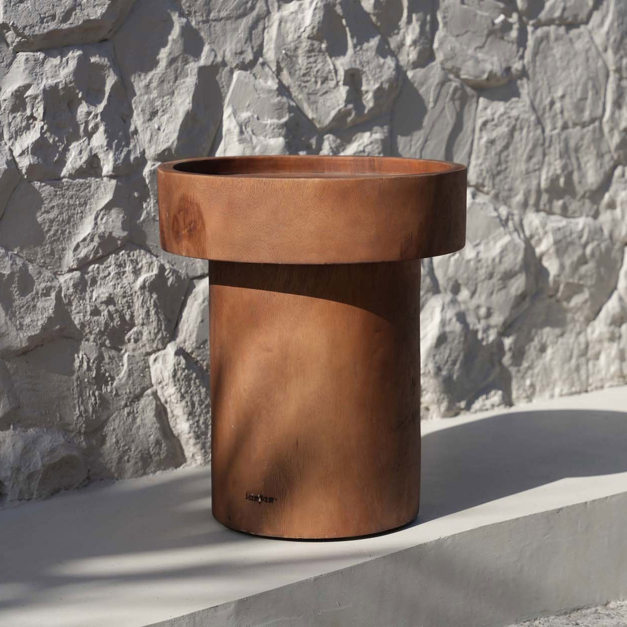Cylindrical side table against a stone wall