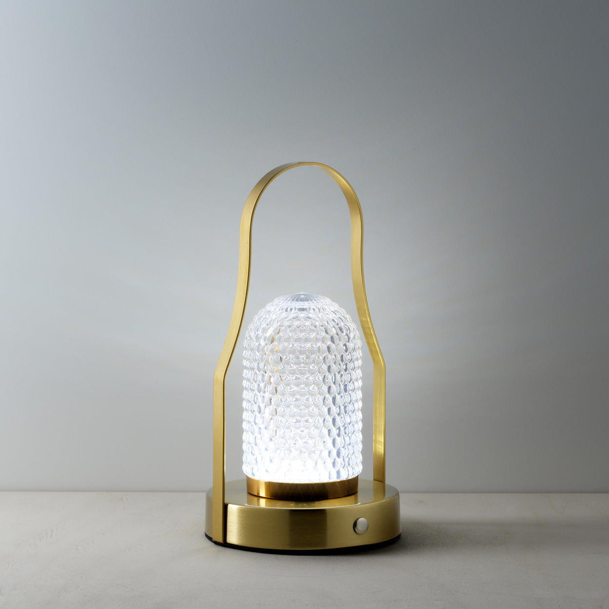 Decorative lamp with textured glass shade and gold metal frame on a gray background