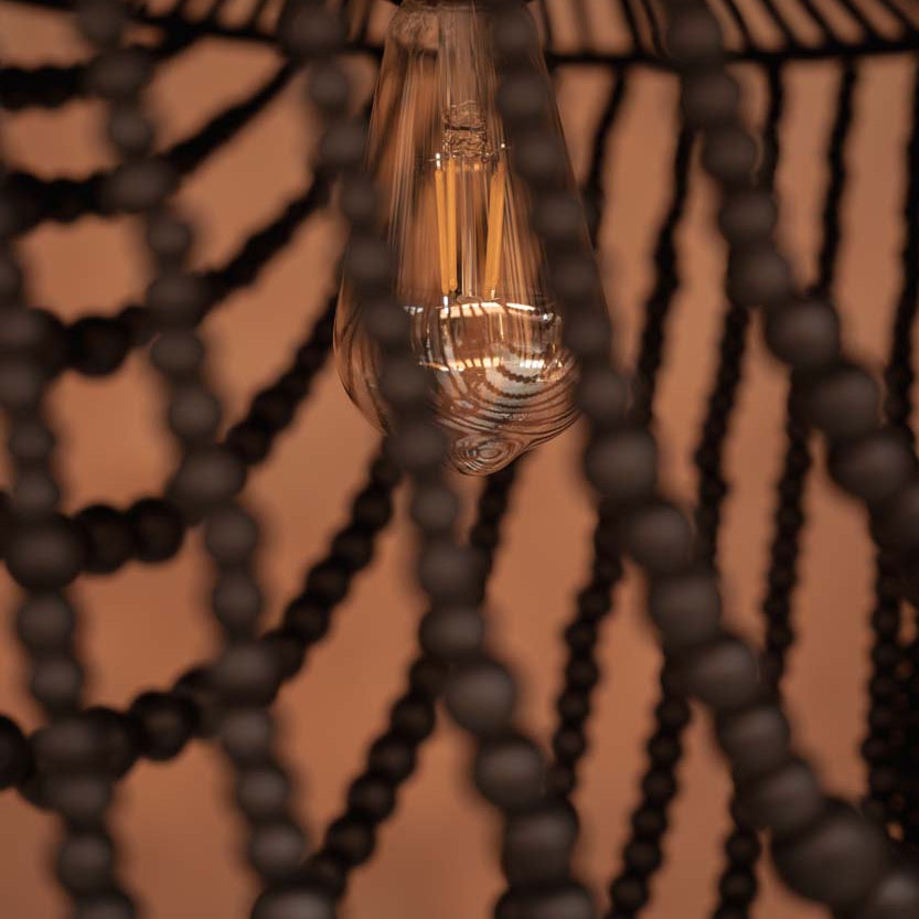 Vintage light bulb hanging from a decorative black beaded chandelier.