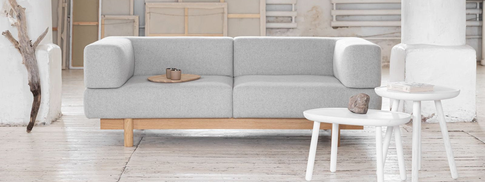 Grey ALCHENIST sofa in a minimalistic room with white walls and wooden floor.
