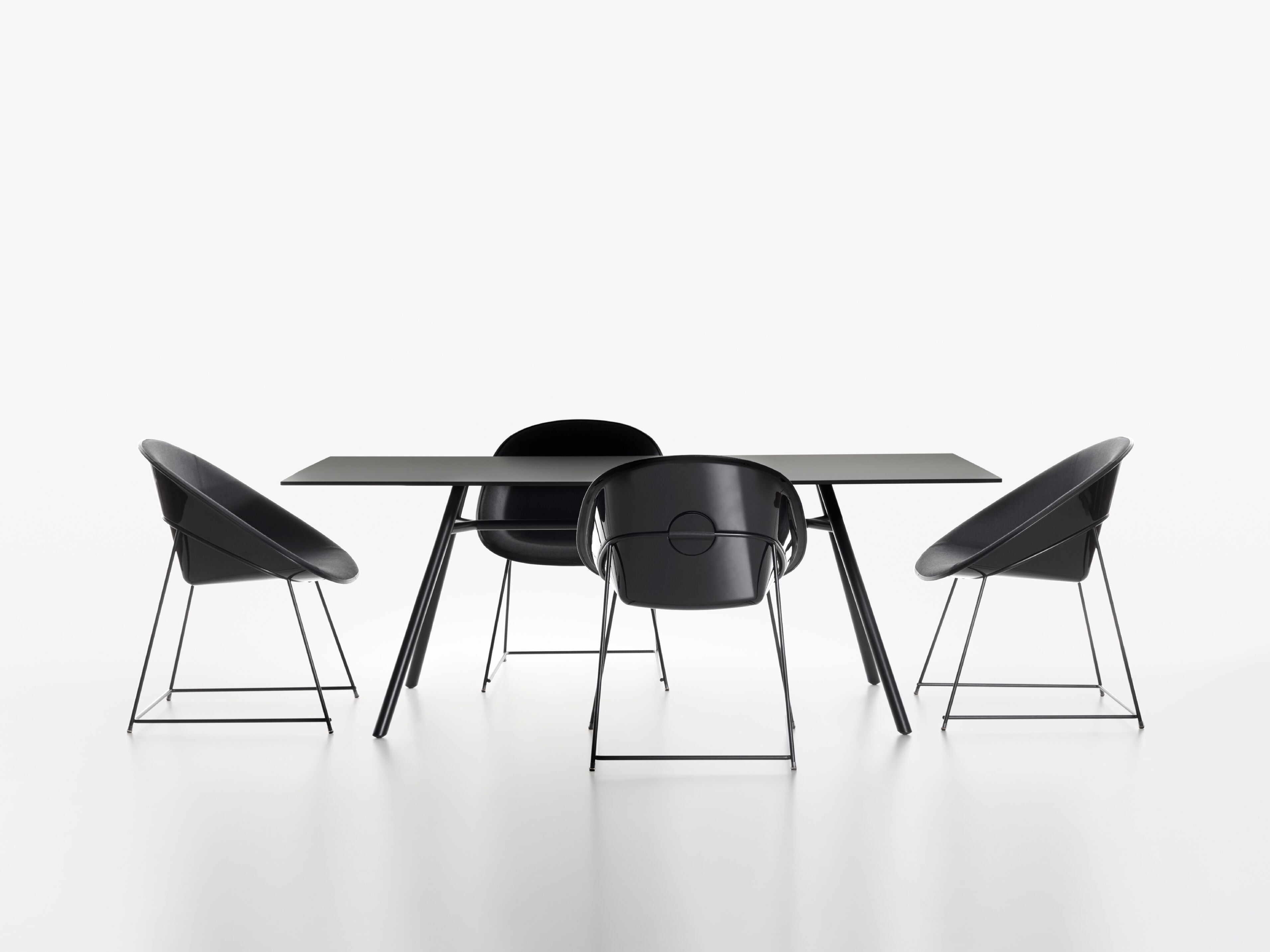 A modern dining set featuring a rectangular black MART table and four matching black chairs with thin metal legs on a seamless white studio background.