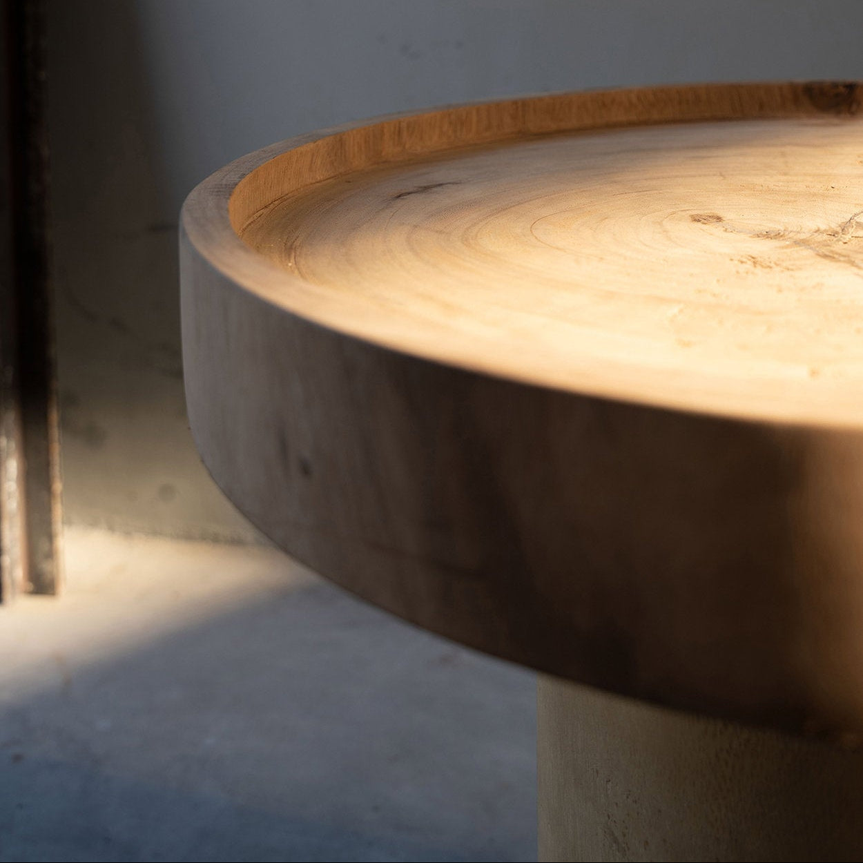 Close-up of wooden side table with a circular design on a plain background