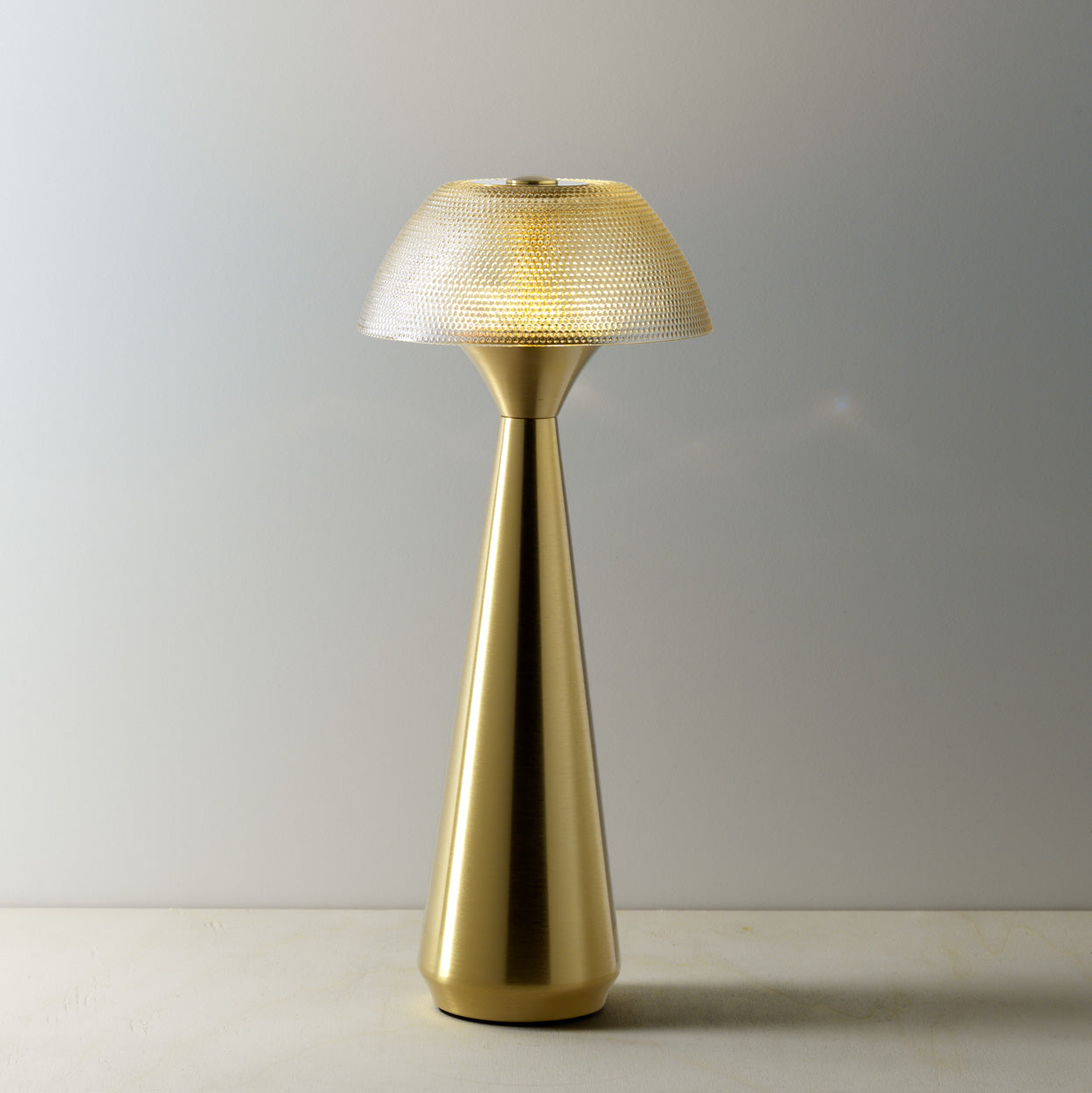 Gold table lamp with textured shade on a warm background