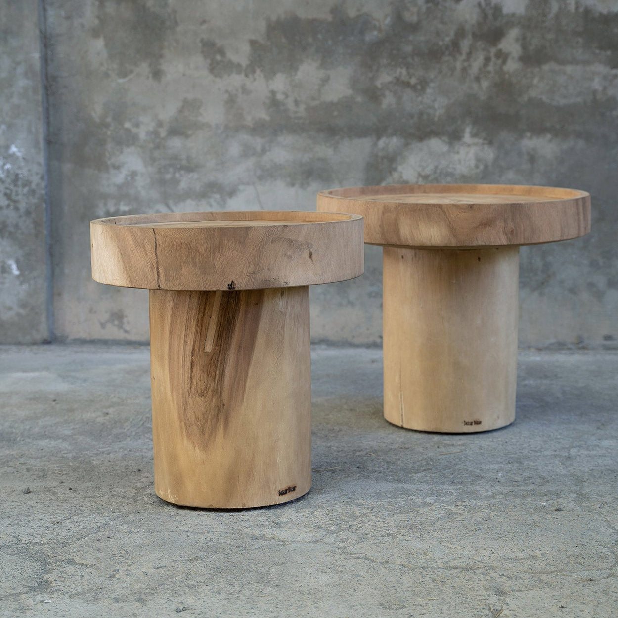 Two wooden side tables against a concrete wall