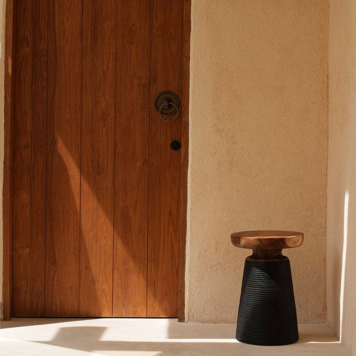 Wooden door with a black side table in front in a minimalistic setting