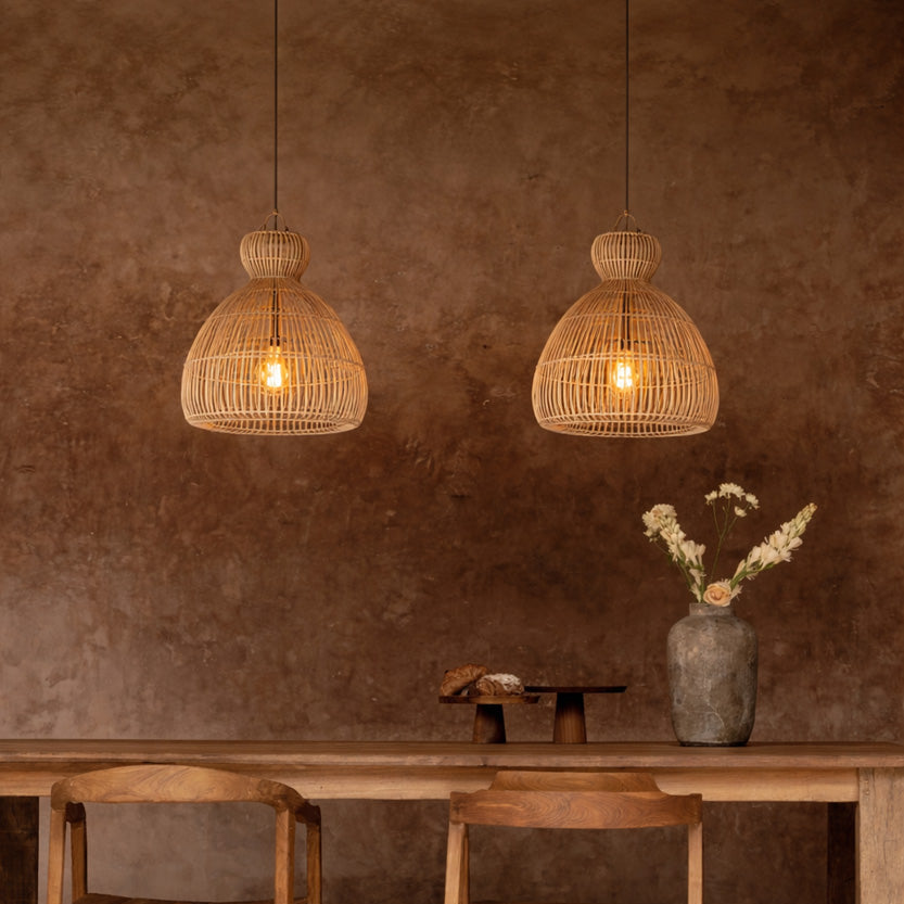 Dining area with wooden table, chairs, and hanging rattan lights against a brown wall.