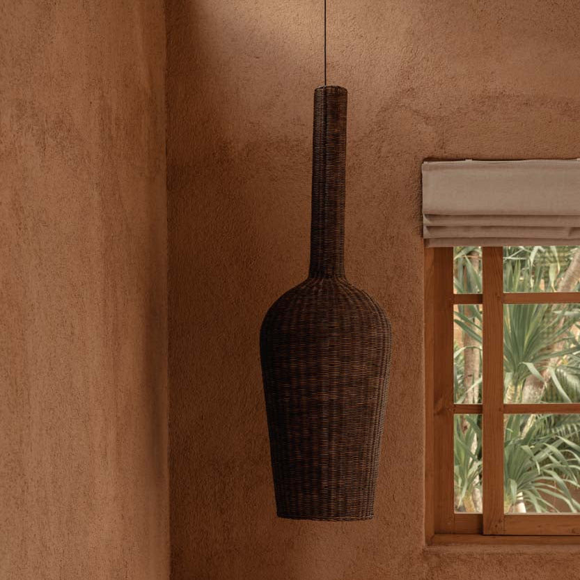 The Amphora Pendant - dark walnut against a textured wall with a window.