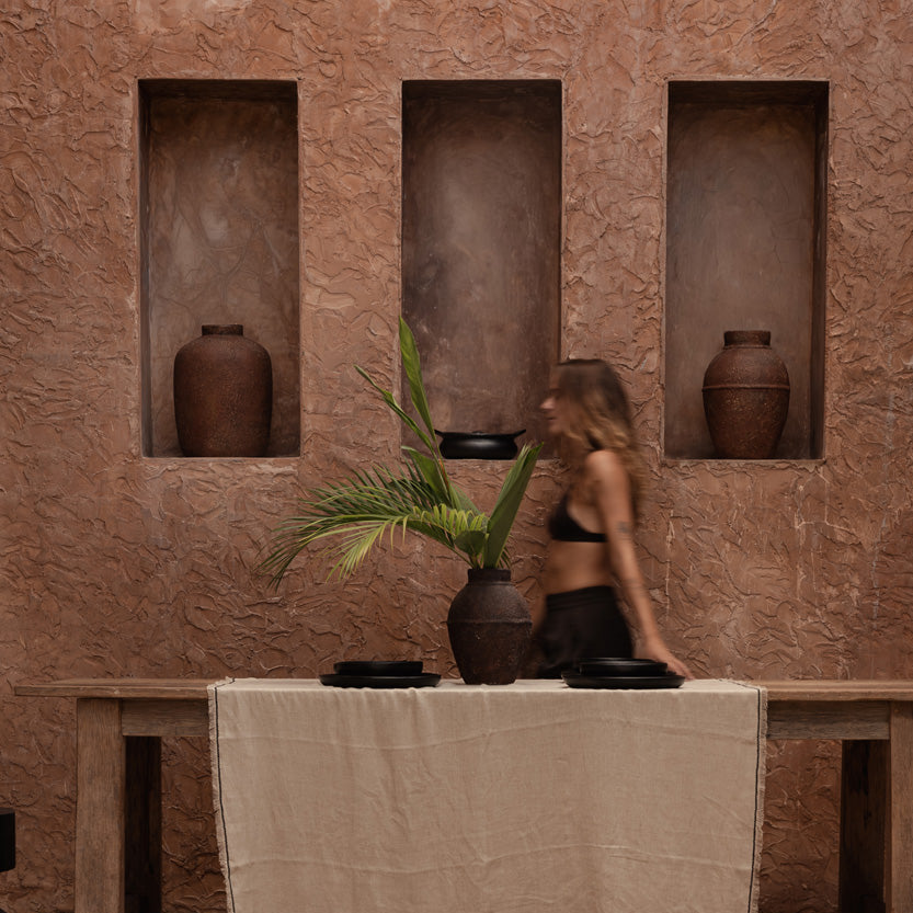 Woman standing in a room with stone walls and decorative vases