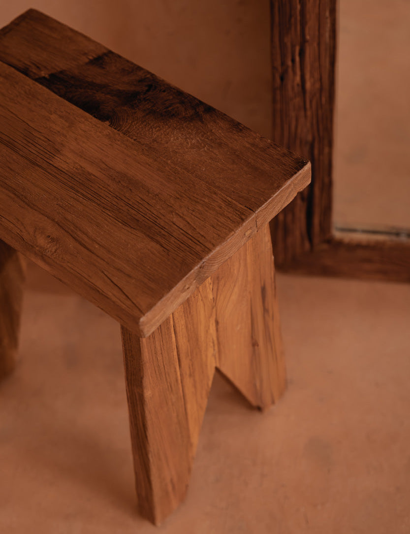 Wooden stool against a brown wall