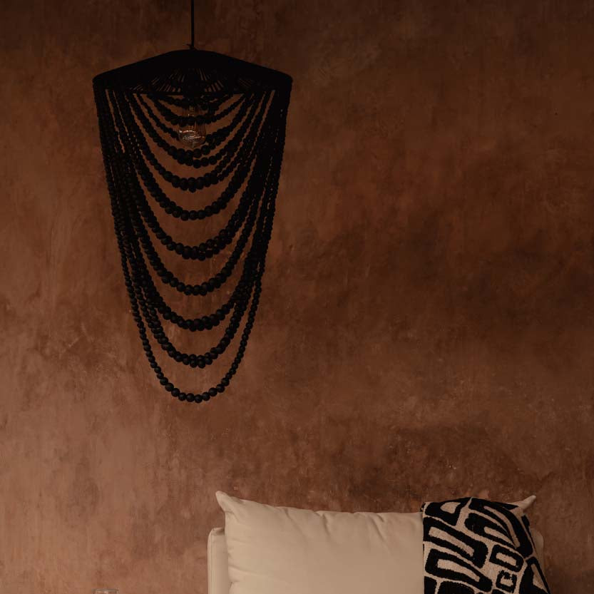 Sofa with a blanket against a brown wall with a decorative light fixture.